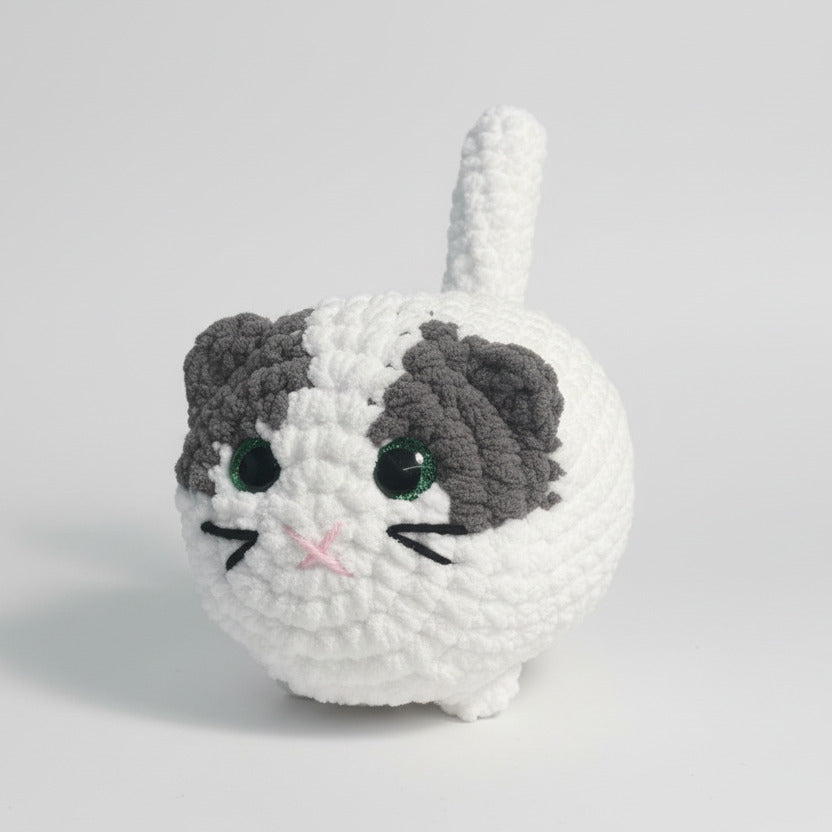 Crocheted cat plush toy on a wooden table with a blurred background