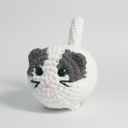 Crocheted cat plush toy on a wooden table with a blurred background