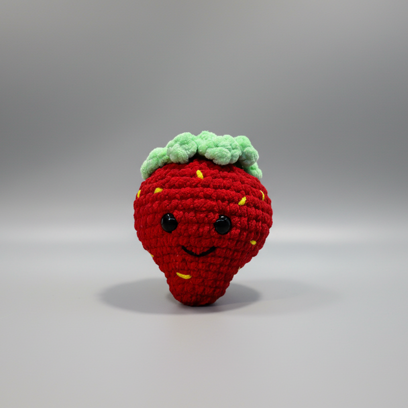 Crocheted strawberry with a face on a white background