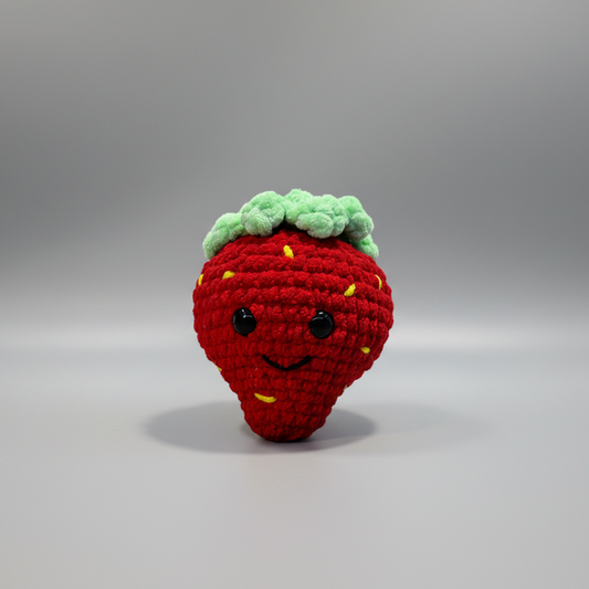 Crocheted strawberry with a face on a white background