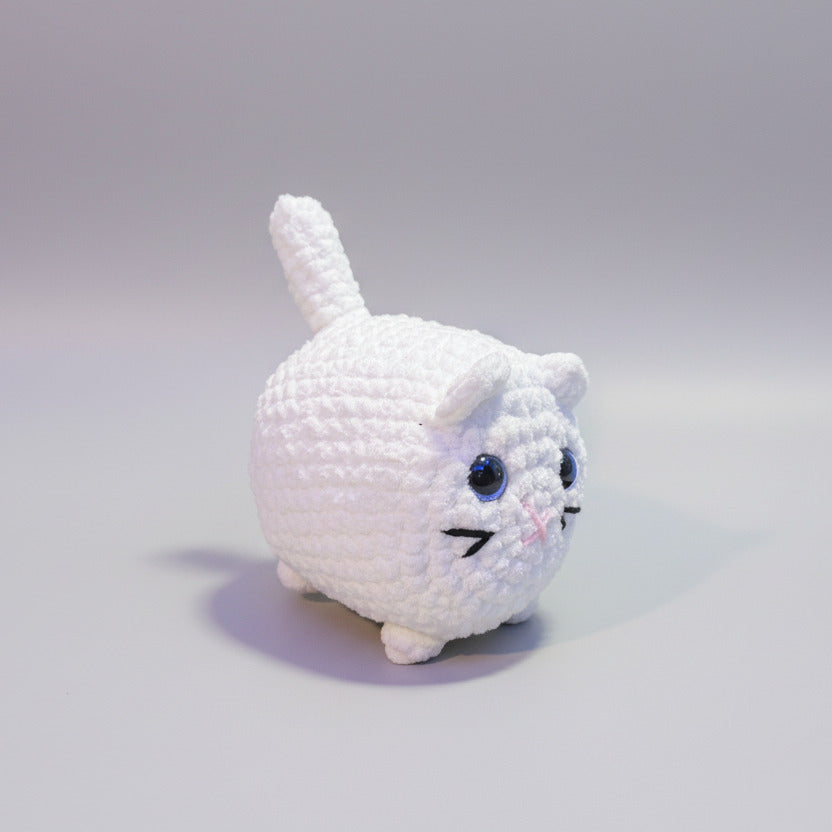 White plush crochet cat with blue eyes on a light gray background