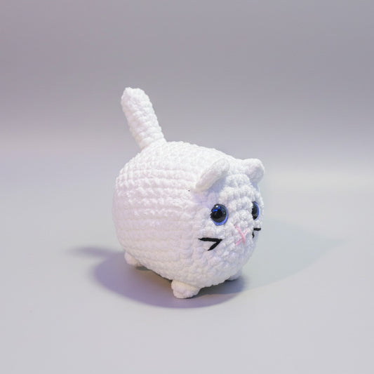 White plush crochet cat with blue eyes on a light gray background