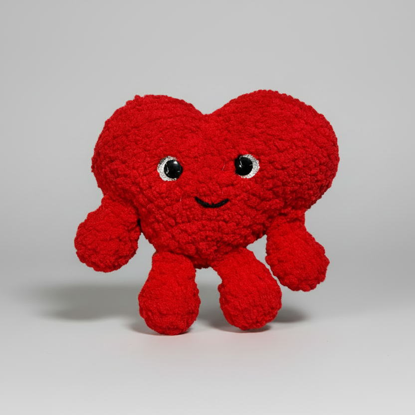 Red Heart crochet plush toy with a smiling face on a white background