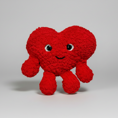 Red Heart crochet plush toy with a smiling face on a white background
