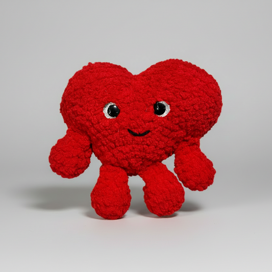 Red Heart crochet plush toy with a smiling face on a white background